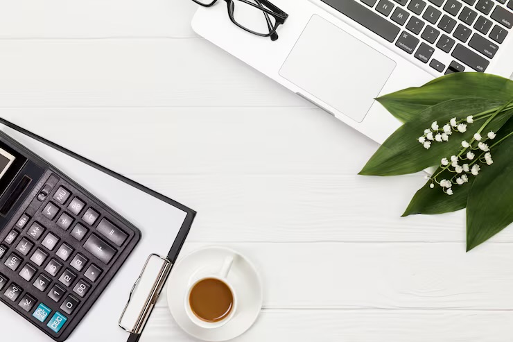 Desk with calculator, laptop, and coffee